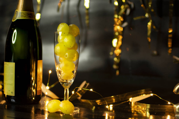 Konzept zum Jahresende. Glas Champagner mit Trauben im Inneren, mit Feiertagsdekoration - Foto, Bild