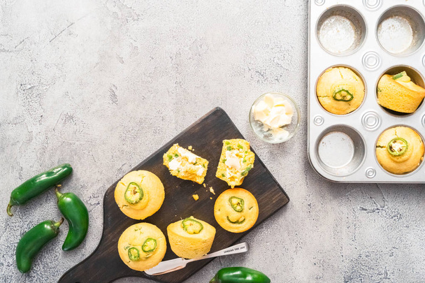 flat lay of freshly baked cornbread muffins with spicy jalapeno peppers and copy space on grey background - Foto, Imagen