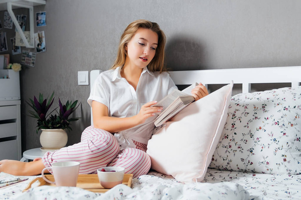 Woman reading book on bed in morning - Valokuva, kuva