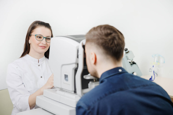 Female doctor ophthalmologist clinic checks eye vision of man on machine lamp. - Fotografie, Obrázek