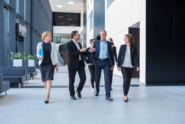 Lively business team walking together in office builging showing teamwork, togetherness and liveliness - Fotoğraf, Görsel