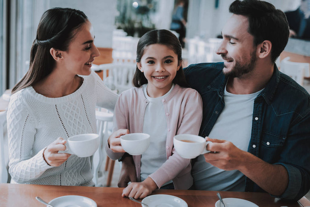 Happy Together. Tea Time. Happy Doughter. Mom. Dad and Daughter. Cupcake. Cafe. Good Relationship. Family Holiday. Active Leisure Time. Cute Relationship. Celebration. Smiling People. Young Family. - Zdjęcie, obraz