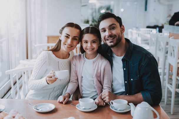 Family Day. Tea Time. Mom. Dad and Daughter. Cupcake. Yummy. Cafe. Happy Together. Good Relationship. Family Holiday. Active Leisure Time. Cute Relationship. Celebration. Smiling People. Young Family. - Valokuva, kuva