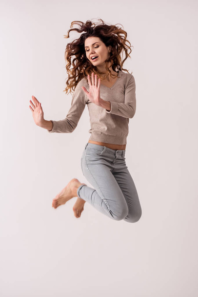 Young emotional pretty girl while jumping on white background smile at camera - Foto, Bild