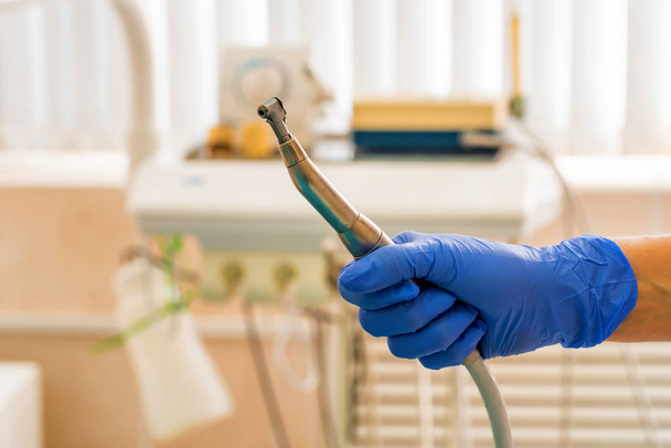 Hand of dentist in glove holds dental drill machine - Foto, afbeelding