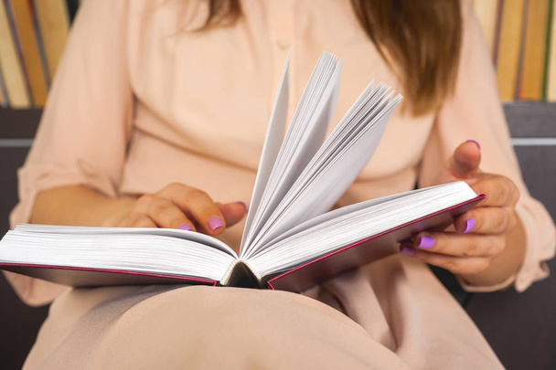 Una joven con un vestido ligero está leyendo un libro. Las manos femeninas sostienen un libro en sus manos
 - Foto, imagen