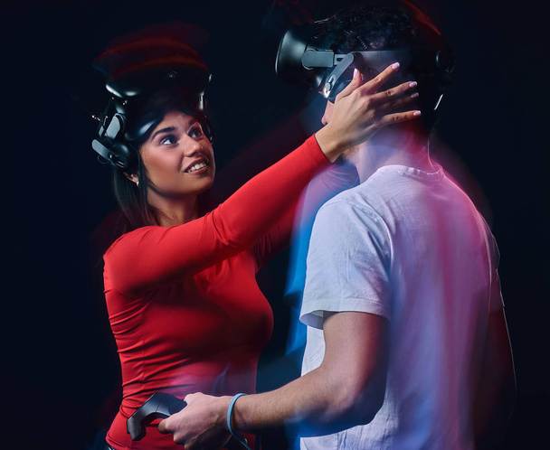 Χαρούμενη κοπέλα ρυθμίζει γυαλιά εικονικής πραγματικότητας με το φίλο της. Ζευγάρι gamers με Vr ακουστικά. - Φωτογραφία, εικόνα