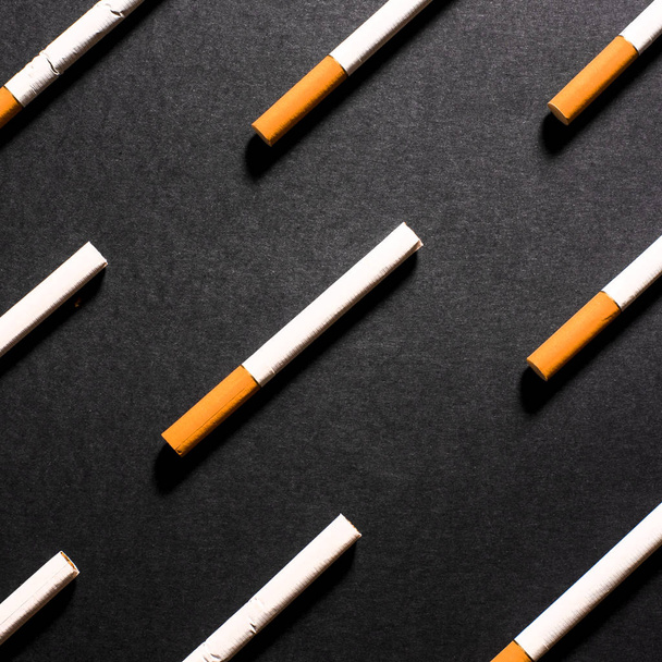 Cigarrillos blancos con filtro naranja alineados en una fila en orden
 - Foto, Imagen