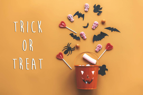 Karkki tai hoitoon teksti merkki. Hyvää Halloweenia. Jack O Lyhty ämpäri loma karkkia, lepakot, hämähäkit, pääkalloja oranssi paperi, tasainen lay. Tekstiavaruus. Kauden onnittelukortti
 - Valokuva, kuva