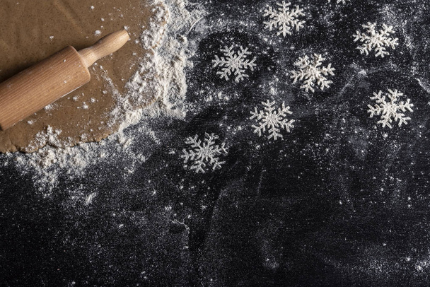 Floury kitchen table with gingerbread dough and snowflakes formed from white flour - Fotoğraf, Görsel