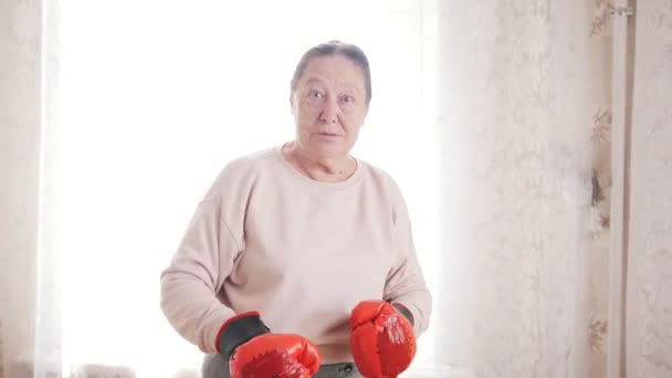 Portrait o old senior woman boxing in front of window - Footage, Video