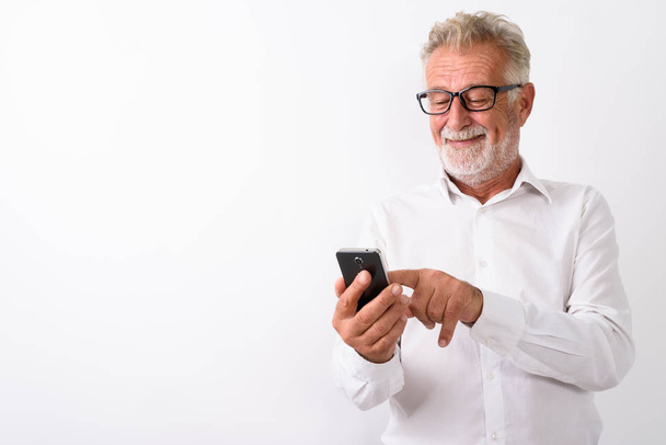 Студийный снимок счастливого бородатого мужчины, улыбающегося при использовании моби
 - Фото, изображение