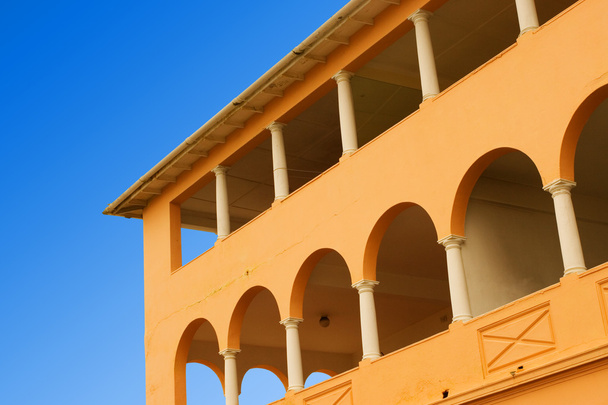 Yellow coloured building with pilars and blue sky - Foto, Imagen