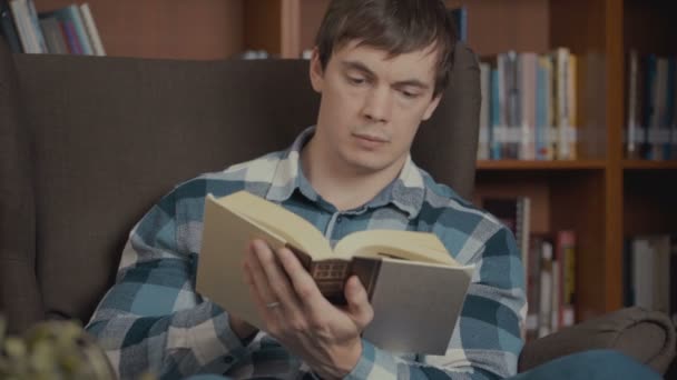 portrét shot muže, čtení knihy poblíž polici v knihovně - Záběry, video