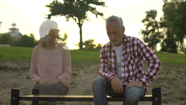 Depressed old man sitting on bench, wife appearing beside, loss sorrow, memories - Footage, Video
