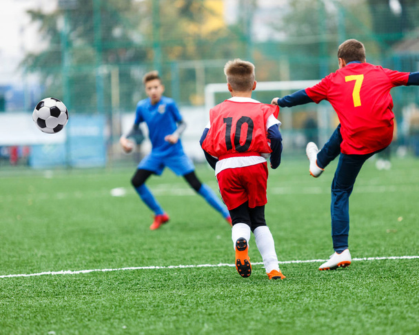 サッカー チーム - 赤、青のスポーツ ウエアで男の子グリーン フィールド上にサッカーします。ドリブルの男の子。ドリブルのスキル。ゲーム、トレーニング、アクティブなライフ スタイル、趣味、子供の概念のためのスポーツをチームします。 - 写真・画像