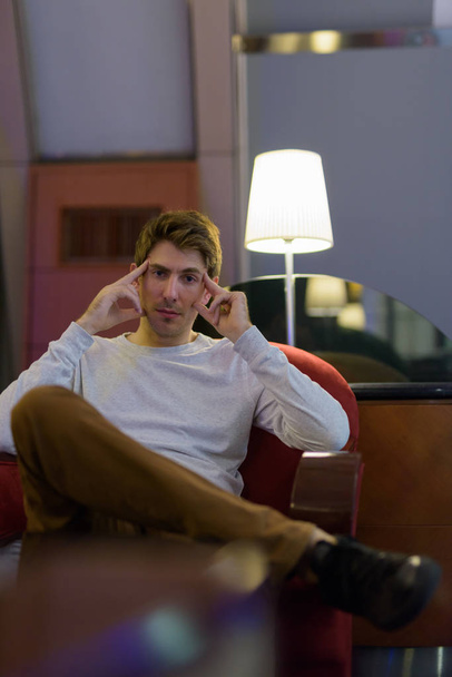 Portret przystojny młody kaukaski mężczyzna siedzący w pomieszczeniu - Zdjęcie, obraz
