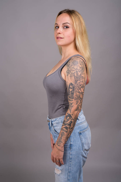 Young beautiful woman with blond hair against gray background - Fotó, kép