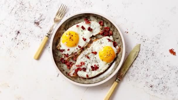 Δύο φρέσκα τηγανητά αυγά με τραγανό τραγανό μπέικον σερβιρισμένα σε ρουστίκ πιάτο - Πλάνα, βίντεο