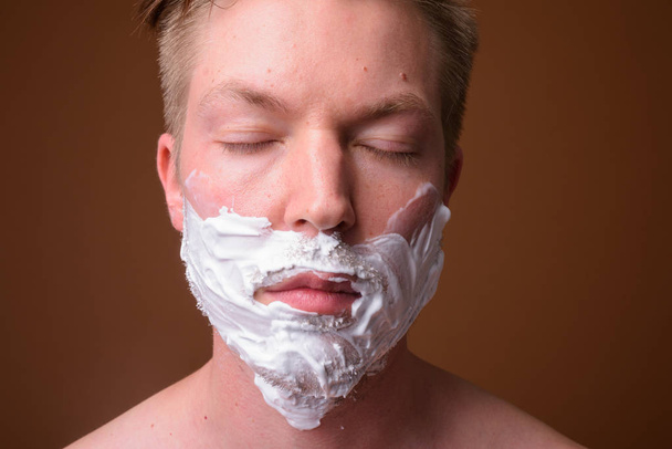 Face of young man shaving his face with eyes closed - Photo, Image