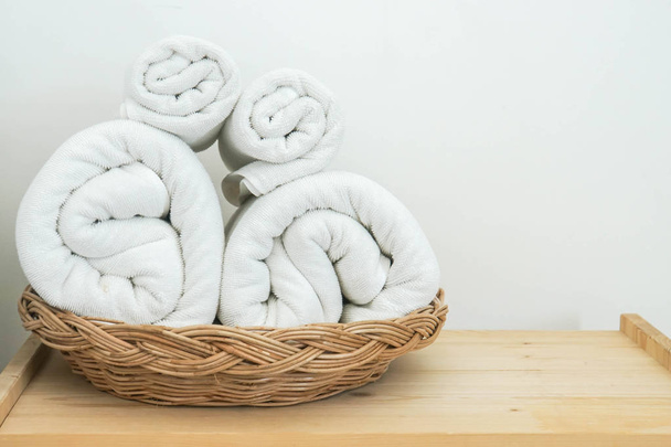 rollos limpios de toalla de algodón blanco en la cesta en el dormitorio para el baño
 - Foto, Imagen
