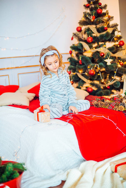 Little girl in pajamas at Christmas morning.Merry Christmas.Little girl rejoices to the Christmas gift - Foto, Imagen