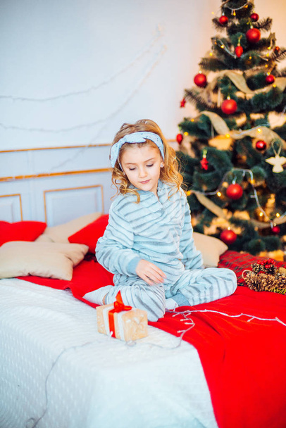 Маленькая девочка в пижаме на Рождество утром. Счастливого Рождества.Маленькая девочка радуется рождественскому подарку
 - Фото, изображение