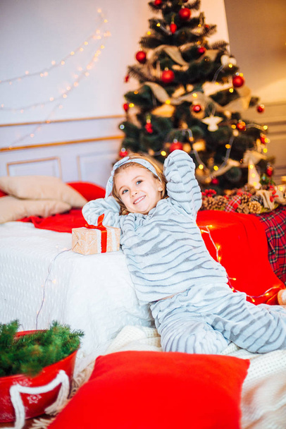 Little girl in pajamas at Christmas morning.Merry Christmas.Little girl rejoices to the Christmas gift - Фото, изображение