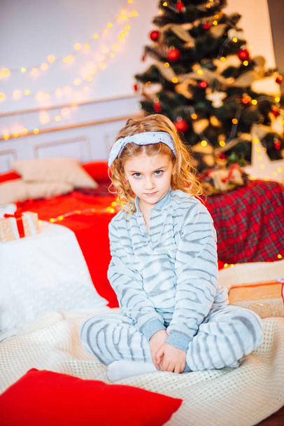 Little girl in pajamas at Christmas morning.Merry Christmas.Little girl rejoices to the Christmas gift - Фото, изображение