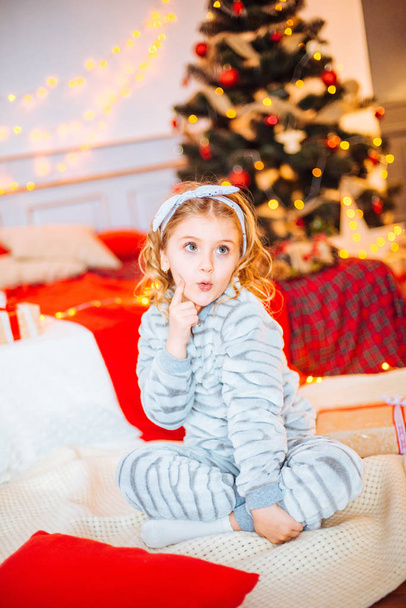 Little girl in pajamas at Christmas morning.Merry Christmas.Little girl rejoices to the Christmas gift - Fotó, kép
