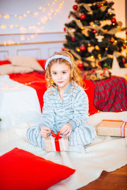 Little girl in pajamas at Christmas morning.Merry Christmas.Little girl rejoices to the Christmas gift - Foto, imagen