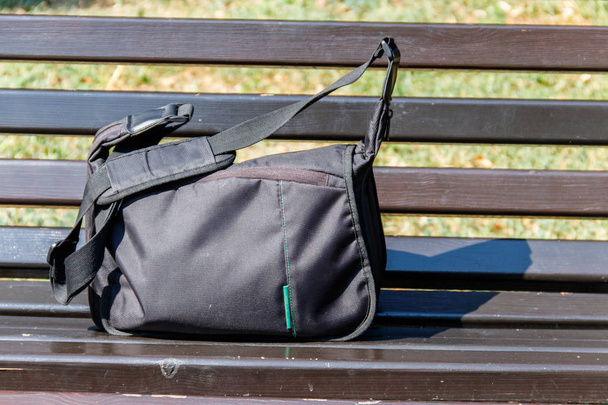 Τσάντα σε ξύλινο παγκάκι στο πάρκο της πόλης - Φωτογραφία, εικόνα