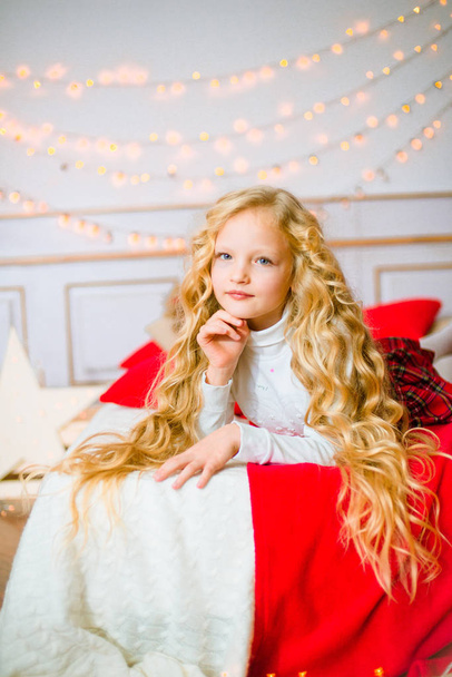 Noel sabahı, sarışın uzun kıvırcık saçlı küçük kız. Neşeli Christmas.Little kız Noel hediyesi için sevinir - Fotoğraf, Görsel