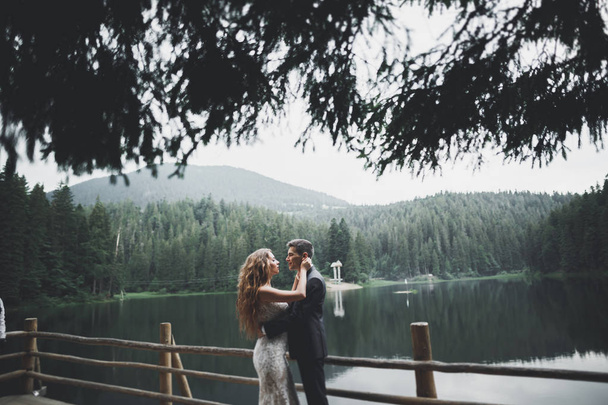 Beautifull wedding couple kissing and embracing near mountain with perfect view - Photo, image