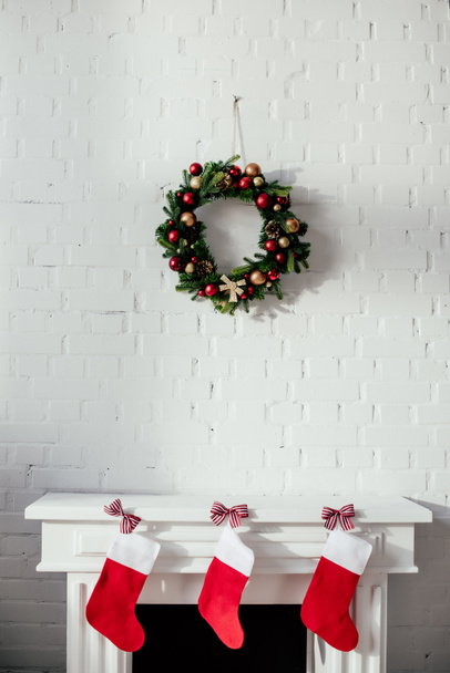 lareira com meias de Natal e coroa de abeto com bugigangas penduradas na parede de tijolo no quarto
 - Foto, Imagem