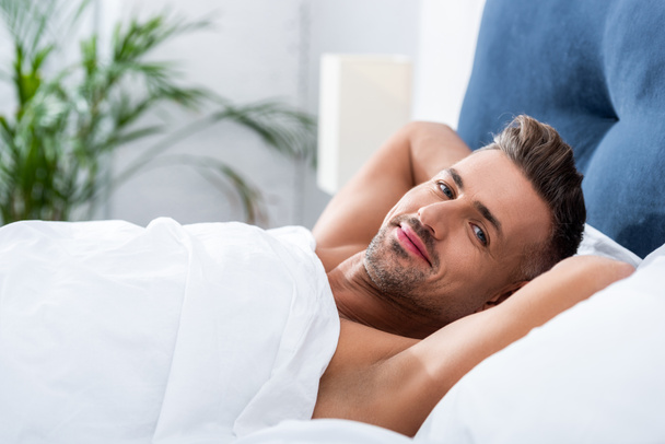 selective focus of happy adult man laying in bed at home  - Photo, Image