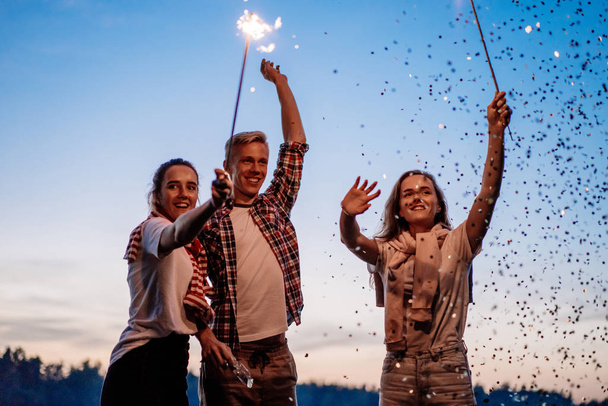 Friends celebrating night party with sparklers and confetti - Valokuva, kuva