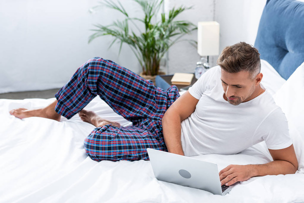 selective focus of male freelancer working in bed during morning time at home - Foto, Imagen