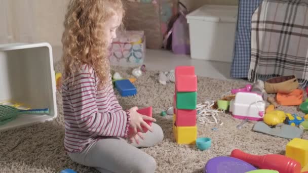 Lovely laughing little kid, preschool blonde, playing with colorful toys, sitting on the floor in the room - Záběry, video