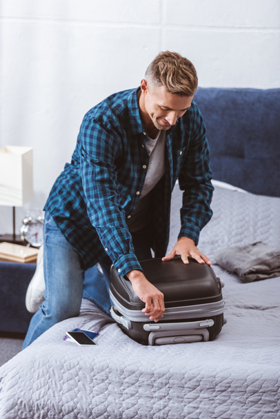 boldog felnőtt ember csomagolás utazótáska hálószobás otthon - Fotó, kép