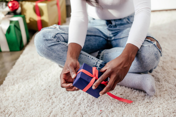 cropped image of african american woman holding christmas gift at home - Foto, immagini