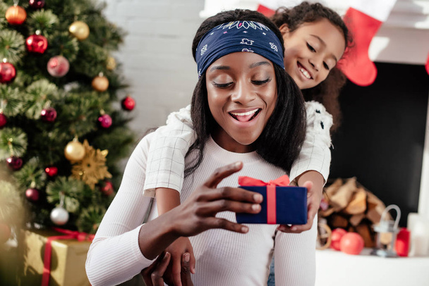 щасливі афро-американських дочка gifting Різдвяний подарунок для матері вдома - Фото, зображення