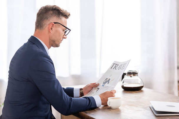 vista lateral do homem de negócios em terno e óculos lendo jornal em casa
 - Foto, Imagem