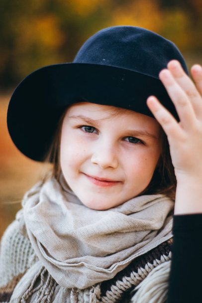 Portrait of smiling girl in poncho and hat walking by autumnal field - Photo, Image