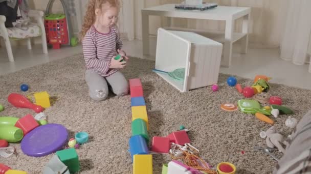Πολυ γέλιο μικρό παιδί, προσχολική Ξανθιά, παίζει με τα πολύχρωμα παιχνίδια, κάθεται στο πάτωμα στο δωμάτιο - Πλάνα, βίντεο