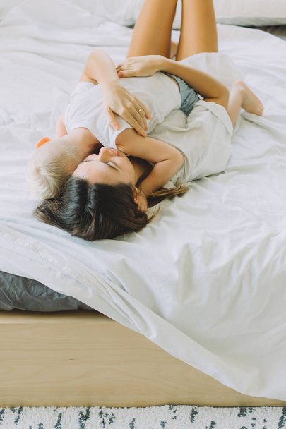Happy loving family. mother hugging her son in the bedroom lying on the bed - Photo, image