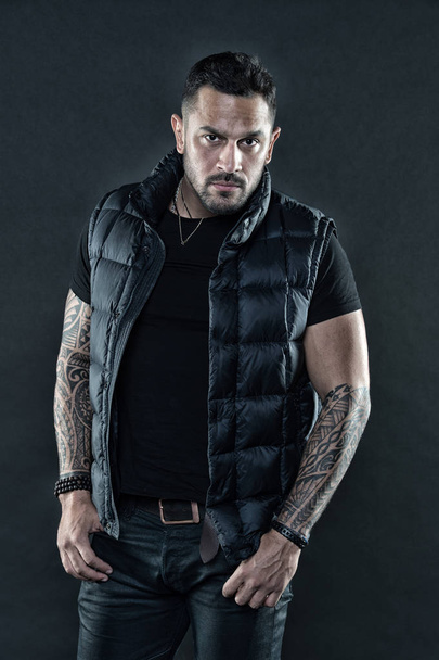 Man brutal unshaven hispanic appearance tattooed arms. Bearded man posing with tattoos. Macho unshaven brutal wear vest. Masculinity and fashion concept. Tattoo brutal attribute. Tattoo art concept - 写真・画像