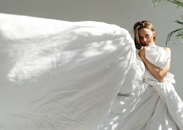 a fehér takaró, a napfény a gyönyörű fiatal nő portréja - Fotó, kép