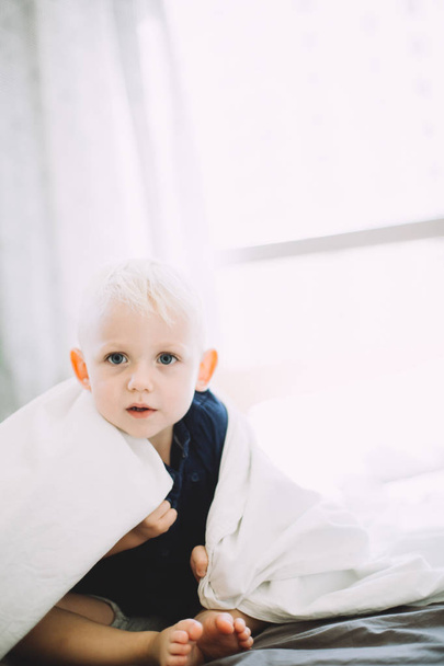 küçük çocuk battaniyenin altında gizleme kamera bakıyor - Fotoğraf, Görsel