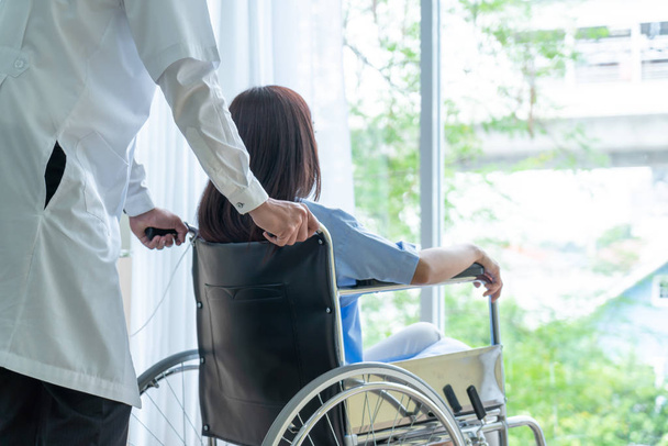 Азиатская пациентка в инвалидной коляске со старшим врачом
 - Фото, изображение